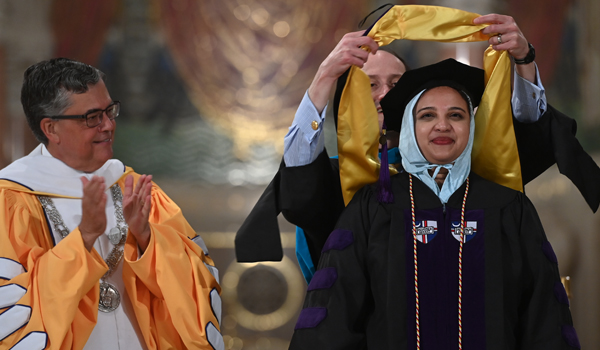 Student receiving diploma and being hooded